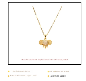 Detail view of a gold elephant pendant necklace with clear zircons and a red stone eye