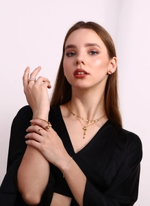 Lifestyle shot of gold bow tie necklace, sparkling rings, and delicate bracelet on model