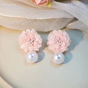 Close-up of pink lace flower earrings with delicate white pearl tassel detail