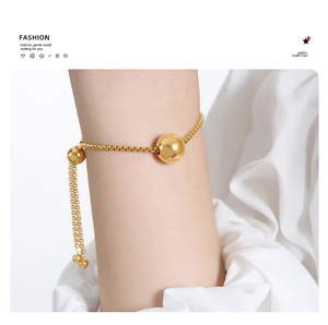 Detail of gold box chain bracelet with sliding ball clasp and polished beads on wrist