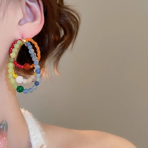 Detail of colorful multilayered beaded hoop earrings worn by a model in warm lighting