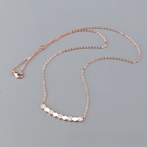 Detail of rose gold hexagon necklace with five inlaid white zircons on cross chain