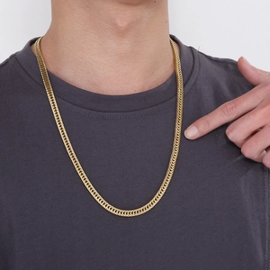 Close-up of a chunky golden hip hop curb chain with polished finish on a male model
