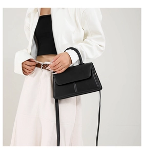 Detail of a chic black PU leather crossbody bag with adjustable strap on a female model