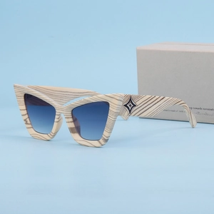 Occhiali da sole cat-eye con lenti sfumate blu e montatura effetto legno su fondo blu