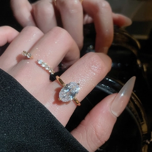 Macro shot of oval-cut zircon gold open ring with side accents on hand with dark background