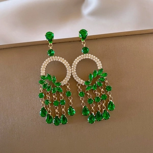 Detail of luxury emerald green teardrop tassel earrings with golden metal work