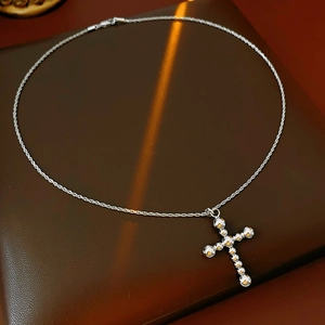 Gros plan d'un collier avec pendentif en croix fait de billes de métal argenté poli