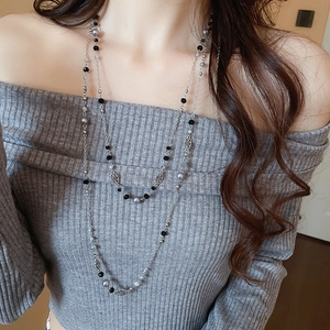 Detail view of double-layer silver flower necklace with black and grey beads on a model