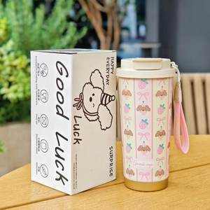 Detail of cute cartoon stainless steel coffee tumbler with matching gift box on wood table