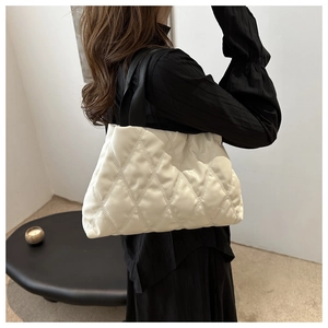 Close-up of beige quilted tote bag with rhombus pattern showing soft padded texture