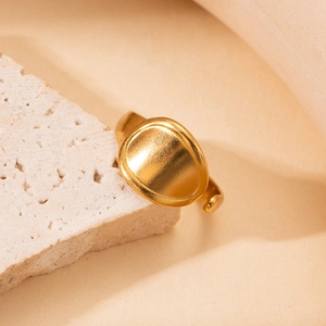 Close-up of a minimalist gold oval-shaped ring displayed on a natural beige stone