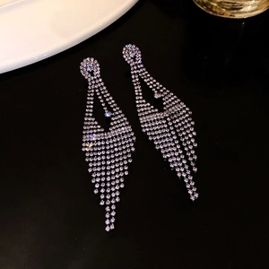 Close-up of silver tassel earrings featuring sparkling rhinestones and a luxury geometric design