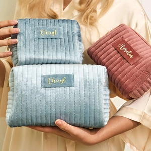 Detail view of quilted velvet cosmetic bags with personalized gold foil names and zipper