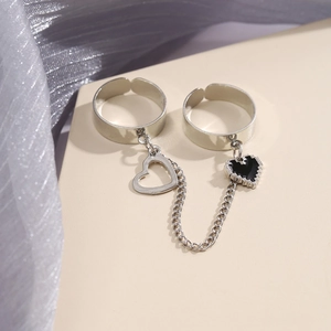 Silver double-finger link ring with heart charms on soft purple silk and beige panel