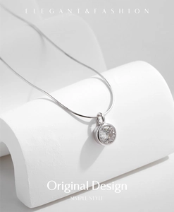 Macro shot of silver snake chain and round bezel-set sparkling zircon necklace pendant