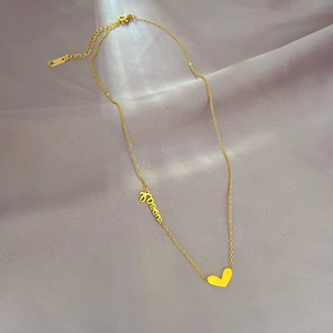 Dettaglio della collana cuore dorata con pendente Forever su sfondo di seta grigia