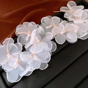 Detailed close-up of white lace mesh flower earrings with gold frame and crystal beads