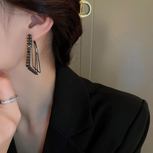 Detail of black geometric layered earrings with cubic zirconia on female model