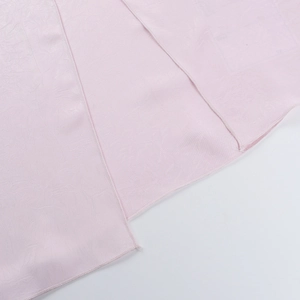 Close-up of pink satin dress showing pleated fabric texture and fine hem stitching details