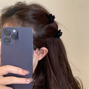 Detail of mini black velvet flower hair clips shown in a mirror selfie style