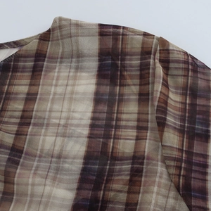 Detail of plaid mesh fabric showing brown vintage pattern and sheer shoulder texture