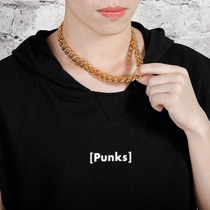Close-up of a gold-toned Cuban link chain necklace on a male model with street style