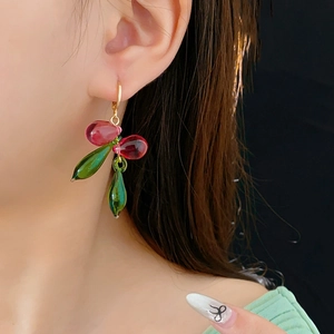 Gros plan de boucles d'oreilles gouttes en verre rouge et vert avec crochets dorés