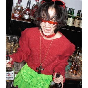 Dark resin cross pendant necklace on a red sweater for a vintage punk fashion look
