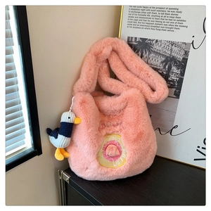 Pink plush tote bag featuring a donut embroidery and cute duck charm in a cozy indoor setting
