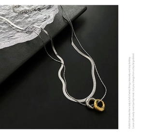 Close-up of double-layer silver snake chain with interlocking gold and silver rings