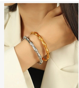 Detail of bamboo joint texture bangles in gold and silver finish on a model's wrist