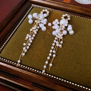 Macro shot of long gold tassel earrings with pearls on vintage green velvet