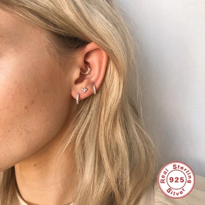 Détail de piercings en argent sterling S925 avec zircons brillants portés sur l'oreille