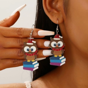 Close-up of cute cat wood earrings with Christmas hat and books on a female model