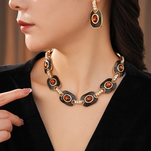 Macro detail of vintage gold enamel necklace and amber oval stud earrings on model