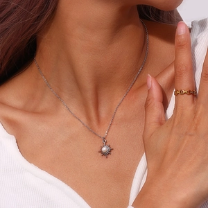 Detail of silver eight-pointed star pendant with pearl on model neck and golden ring