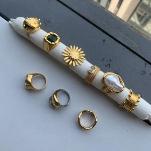 Detail of vintage gold-plated rings with baroque pearls, emerald gems and sun motifs
