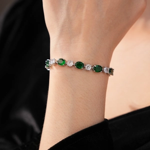Gros plan d'un bracelet en argent avec pierres vertes et zircons sur le poignet d'un modèle