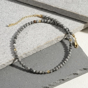 Macro view of natural grey marble stone beads and gold spacers on the necklace