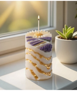 Close-up of a lit lavender candle with floral relief and golden wave patterns