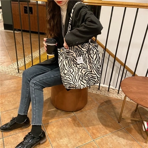 Detail of black and white animal print corduroy tote bag with magnetic snap and brand tag