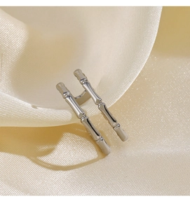 Détail macro d'une bague en argent style bambou sur tissu satiné crème élégant