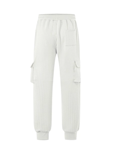 Detail of white quilted jogger pants with waffle texture and cargo flap pockets on side