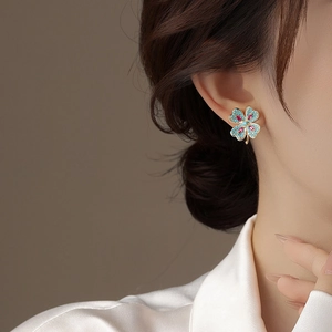 Gros plan détaillé d'une boucle d'oreille trèfle vintage avec pierres bleues et cristaux roses