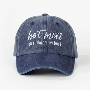 Detailed close-up of hot mess embroidery on washed navy blue cotton baseball cap