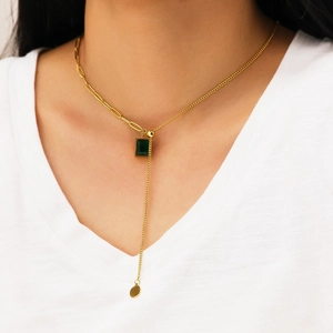 Elegant gold necklace with emerald green zircon pendant worn on model with V-neck top
