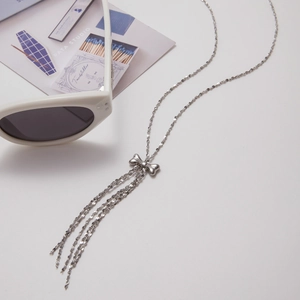 Gros plan d'un collier à pompon argenté avec pendentif nœud sur un fond de style chic