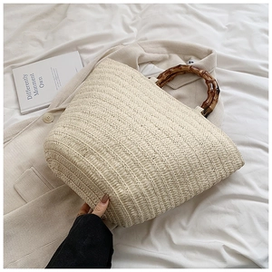 Detail of hand-woven straw tote with natural bamboo handles and rich texture