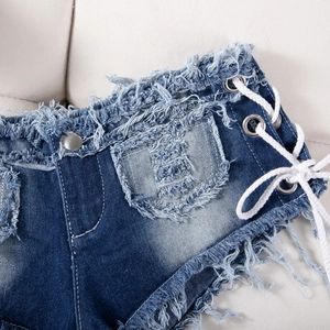 Dettaglio ravvicinato degli shorts in denim blu scuro con bordi sfrangiati e lacci laterali